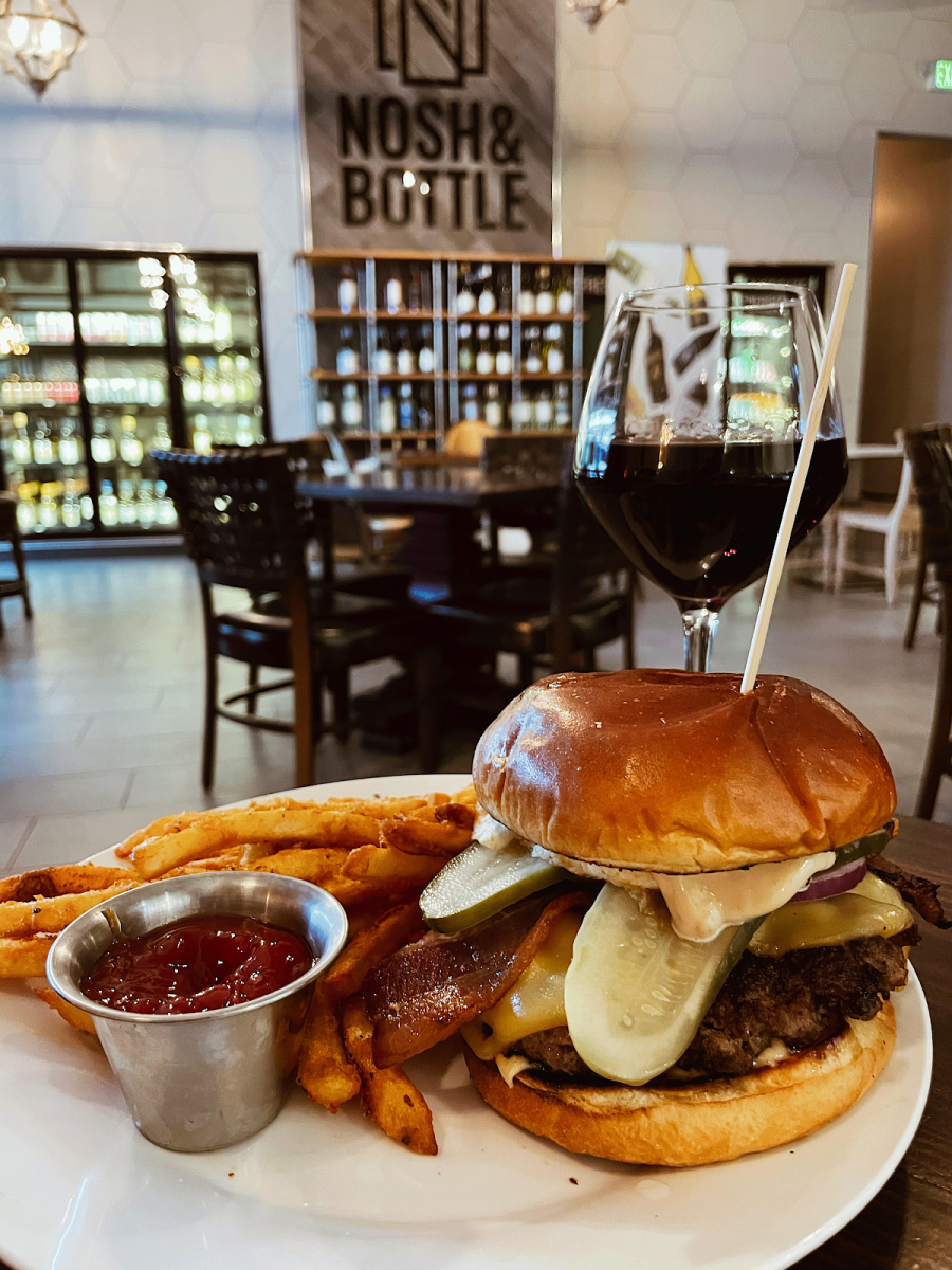 A burger with fries and a glass of wine at Nosh & Bottle at the Toyota Music Factory