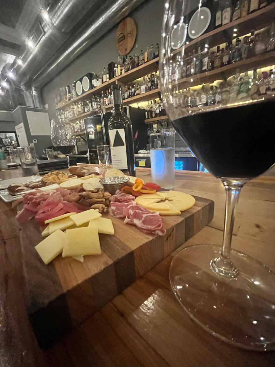 glass of wine with charcuterie board, in front of bar