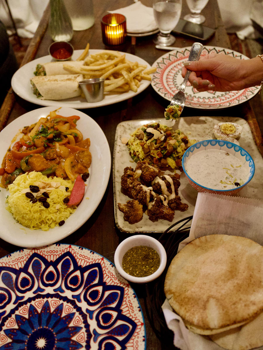 An array of Mediterranean cuisine sits on a table with colorful dishes at Zooroona.