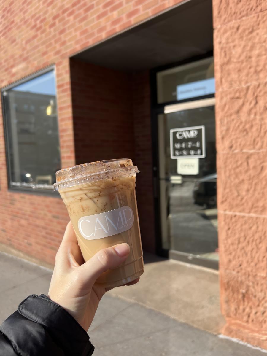 a hand holds a to-go cup of iced coffee
