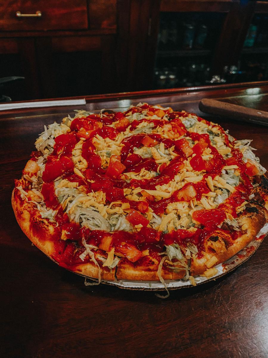 a pizza featuring taco ingredients with a swirl of hot sauce