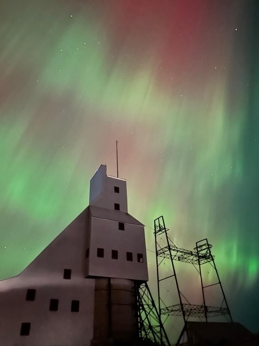 the northern lights dance against the mining hoist house