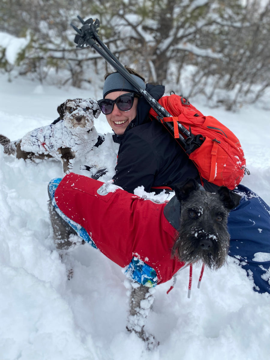 Girl laying in the snow with dogs