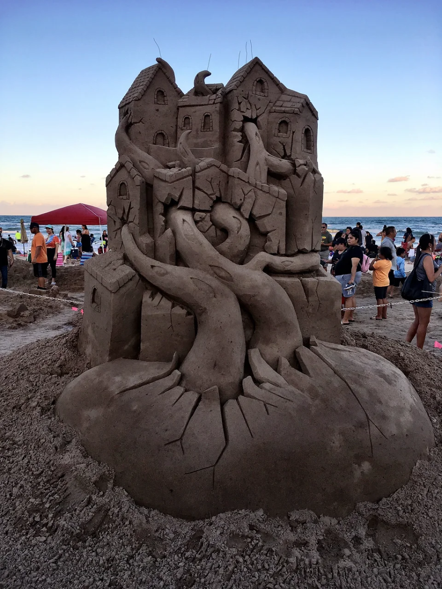 Sand sculpture showing a tree root that is growing through a house