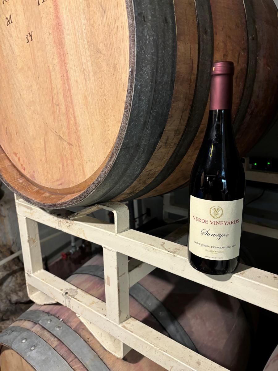 Bottle of wine next to wine barrel at Verde Vineyard