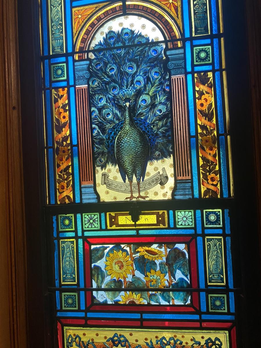 stained glass window with a peacock over yellow sunflowers