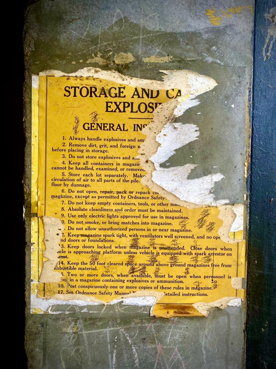 old torn up storage and explosives yellow direction sheet from a military base taped to the wall