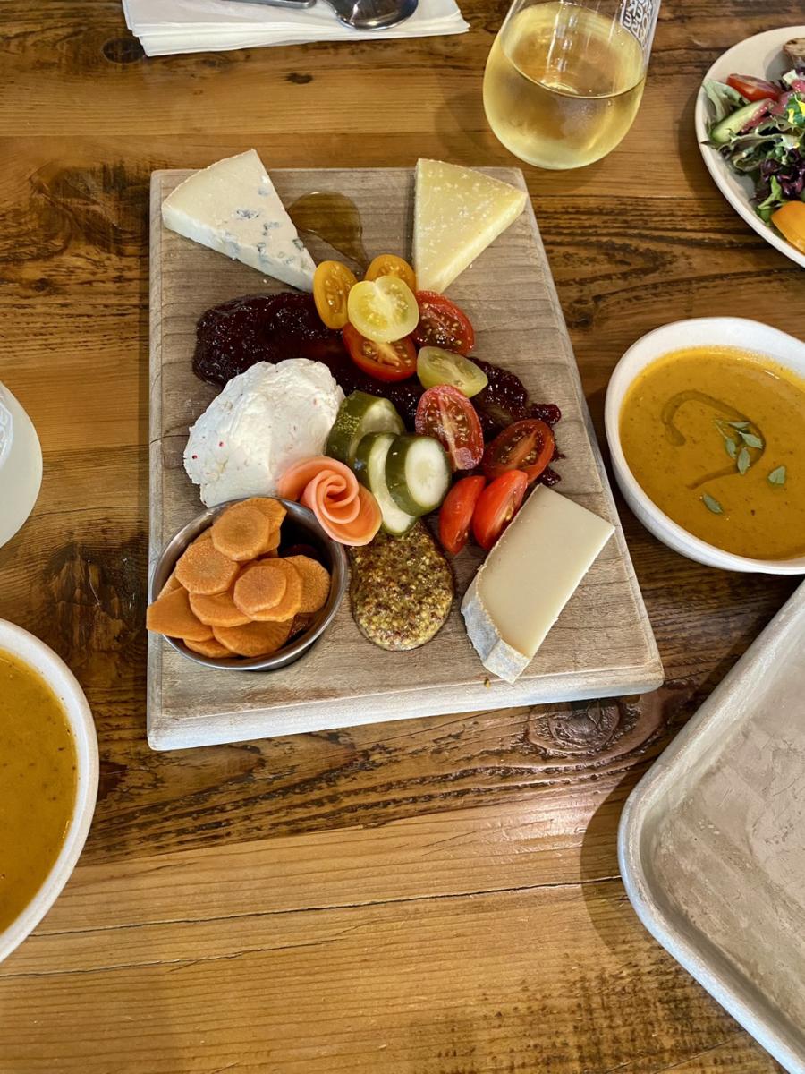 Cheese and pickled vegetable charcuterie board on a wooden slab and rustic table