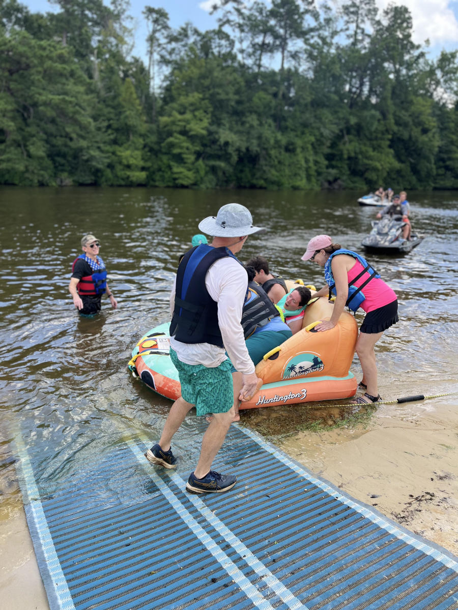 Volunteers with Ski Dawgs and Ainsley's Angels help PJ Paulsell transfer into an adaptive watercraft at the Pearl River, making an on-the-water recreation experience possible.