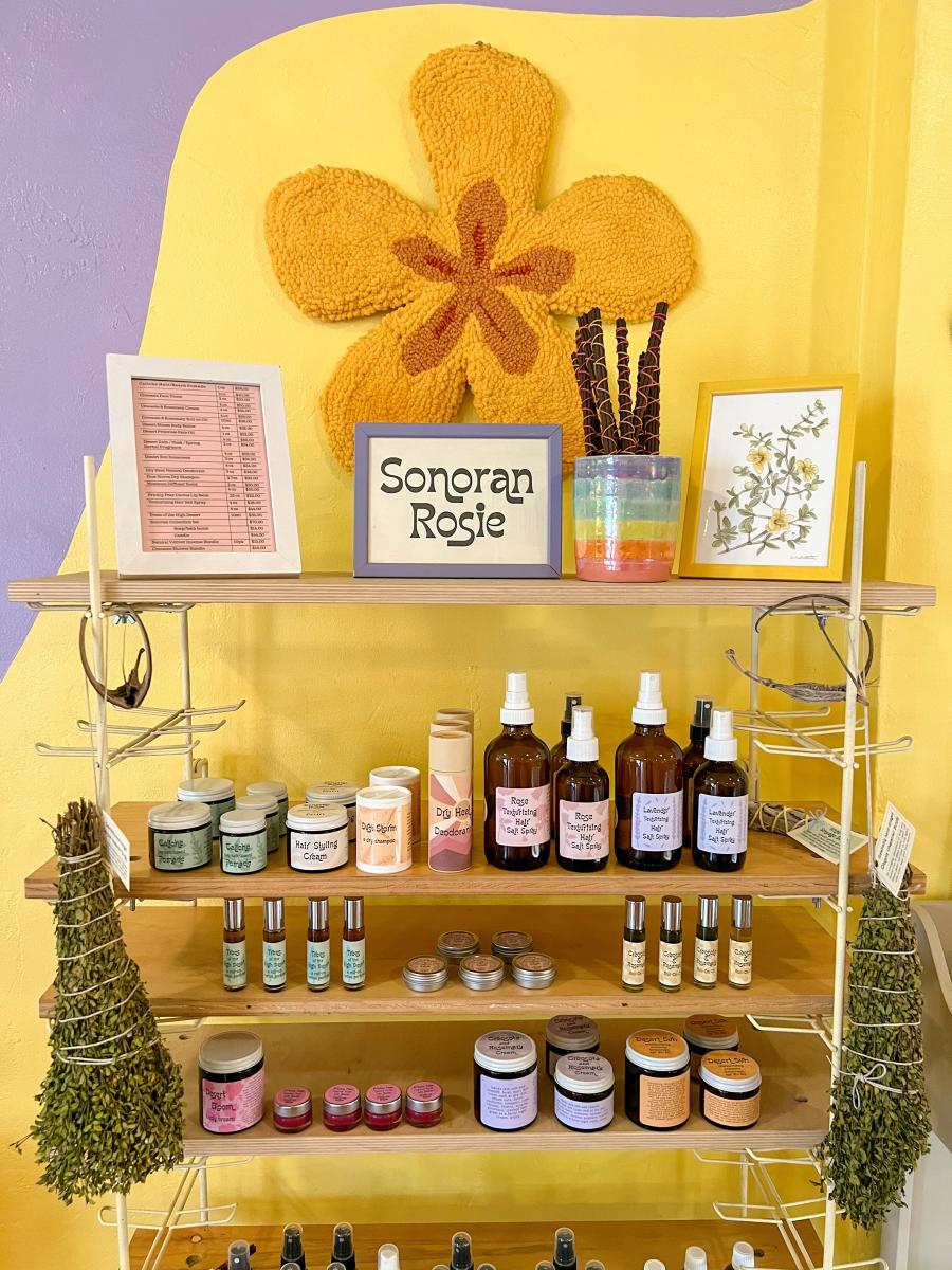 brightly colored shop with a shelf that says Sonoran Rosie. On the Shelf is a collection of self care goods and beauty products