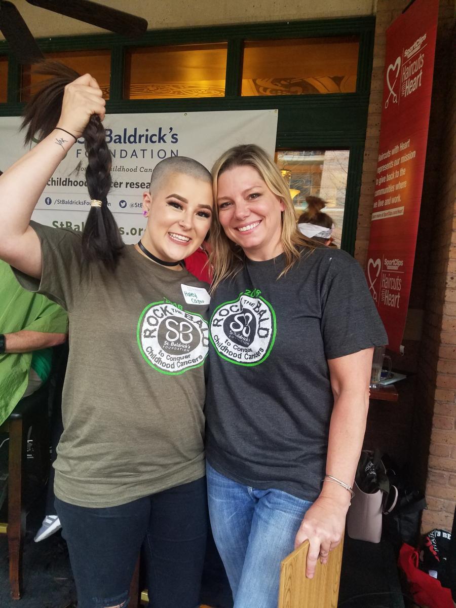 Woman holding ponytail in her hand after having her head shaved for charity fundraiser