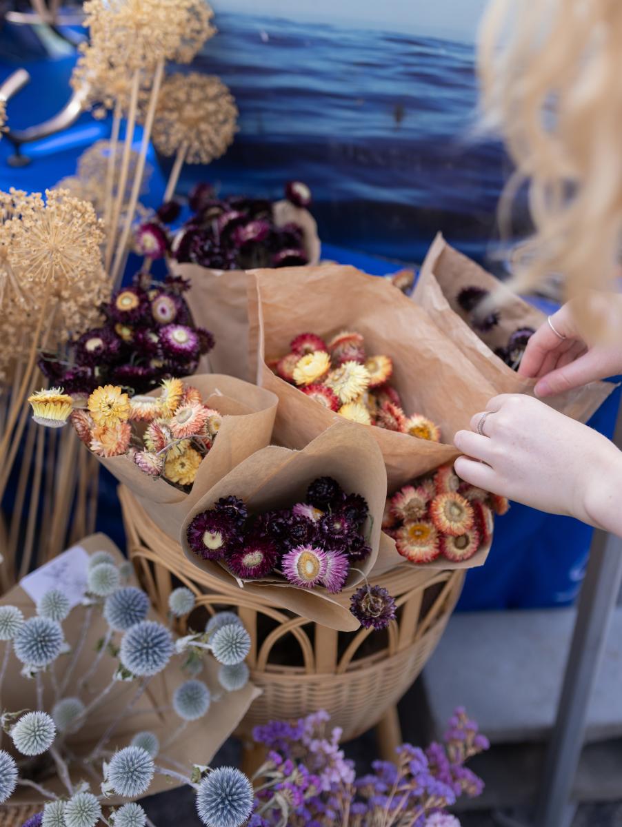 Hand_Reaching_Toward_Bouquets_of_Colourful_Dried_Flowers_at_a_Market_Display