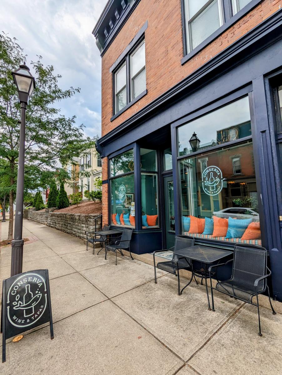 Image is of the building of Conserva with tables and chairs outside.