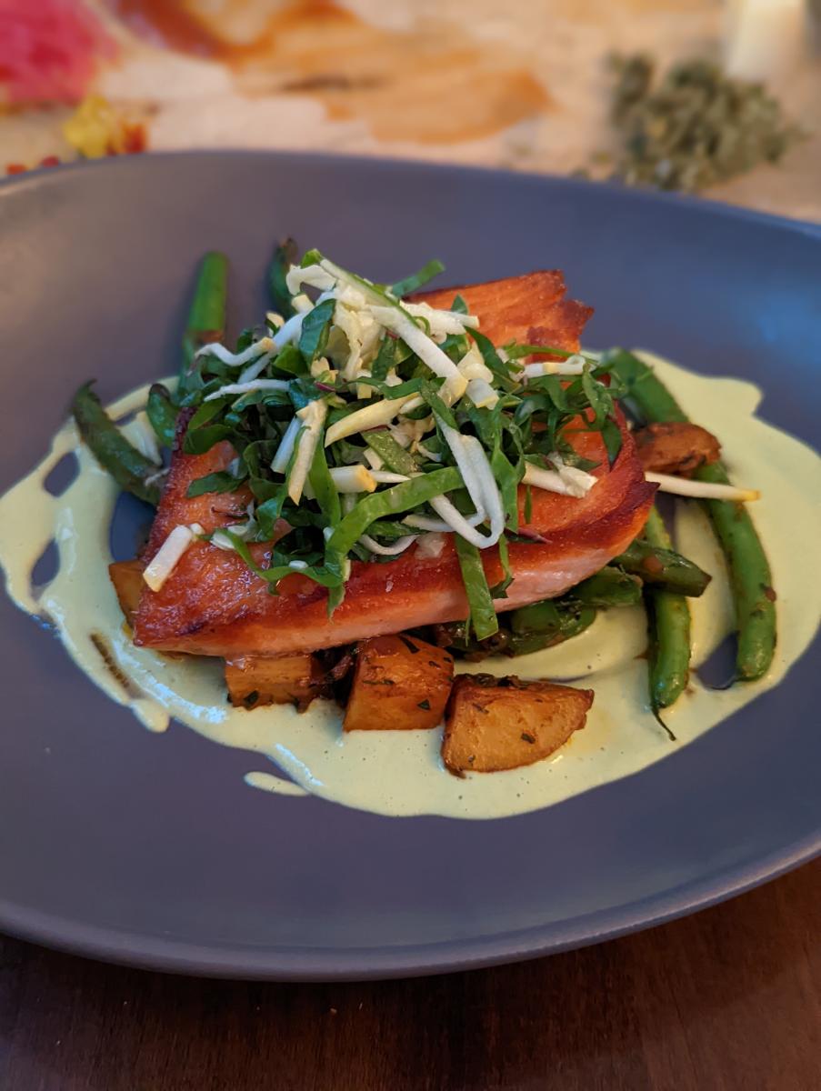 Blue plate with salmon, green beans and potatoes under a drizzle of white sauce at Bouquet Restaurant in Covington, Ky