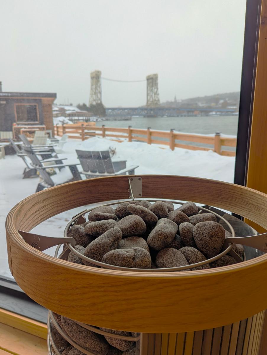a sauna stove in the foreground of a winter view of patio and bridge