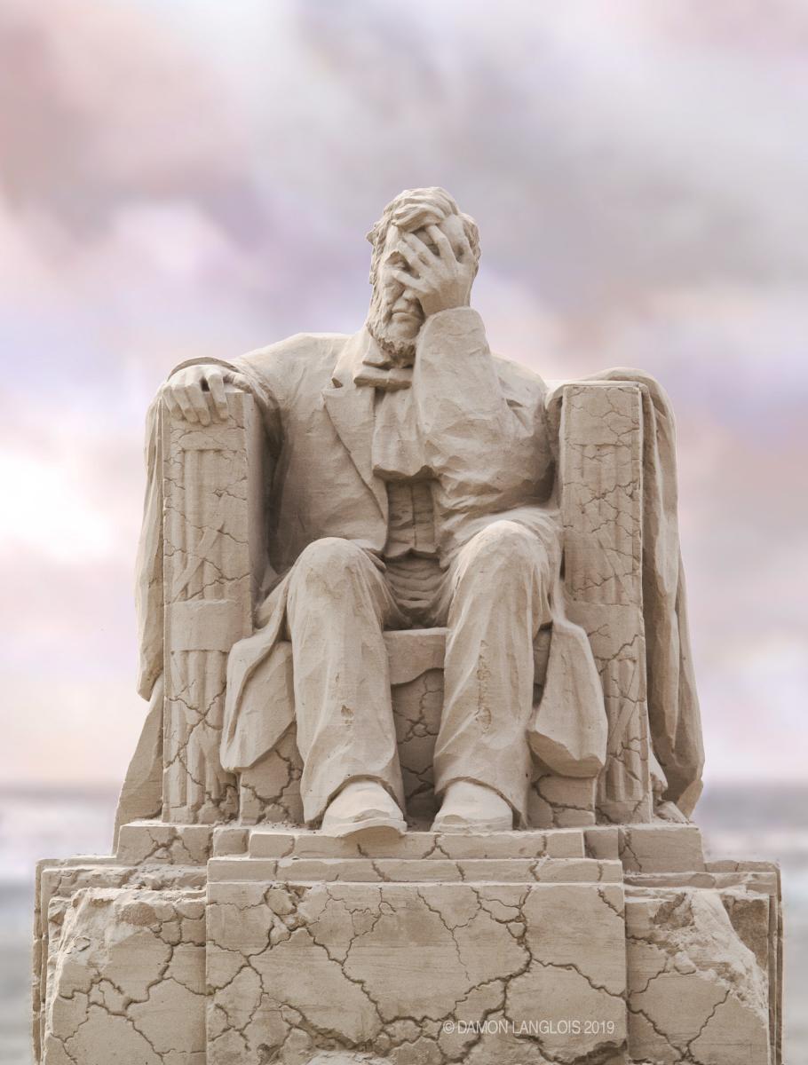 Portrait image of a sand sculpture on the beach of Abraham Lincoln sitting on a crumbling pillared chair with his hand to his face.