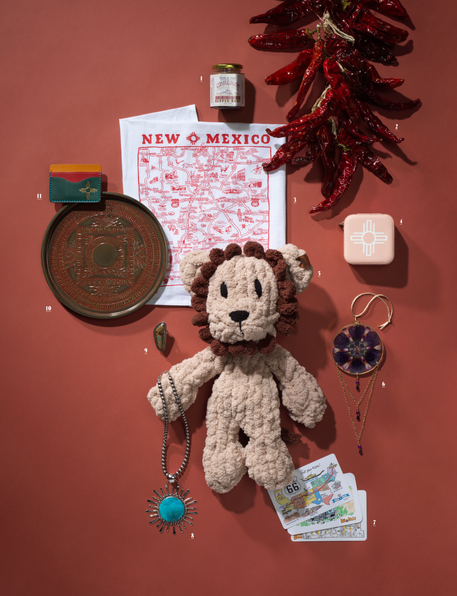 Flat-lay of New Mexico-made products from ABQ Collective, including chile ristras, jewelry, a plush lion toy, honey, and local art items.