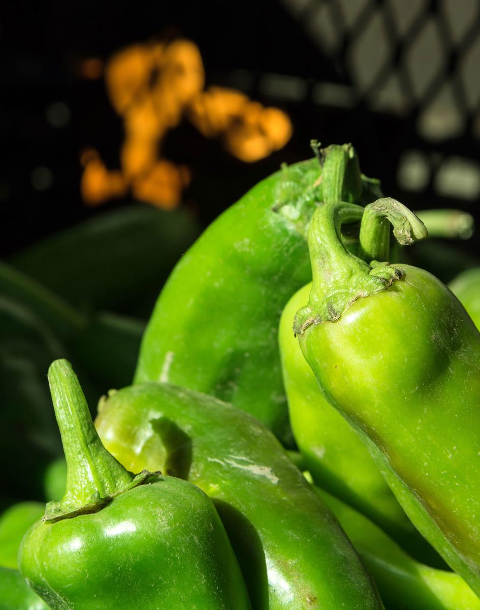 Close up of green chiles with a fire in the background