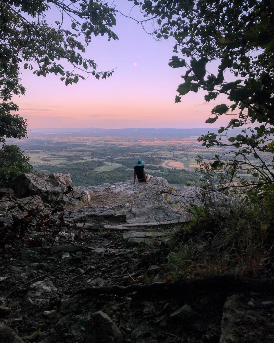 Hiker sitting on a rock overlooking the valley on Flat Rock Trail