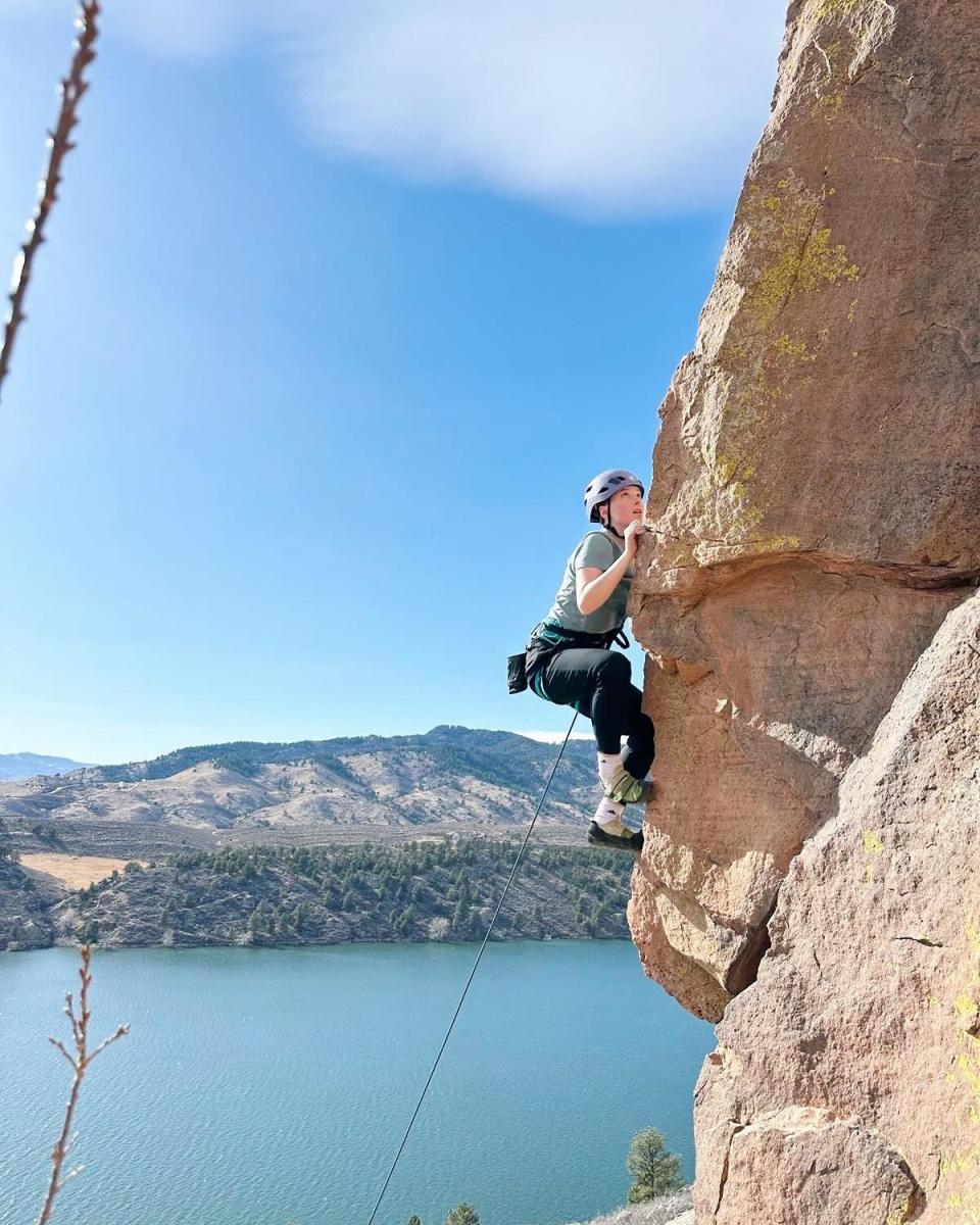 A person rock climbing with a lake in the background