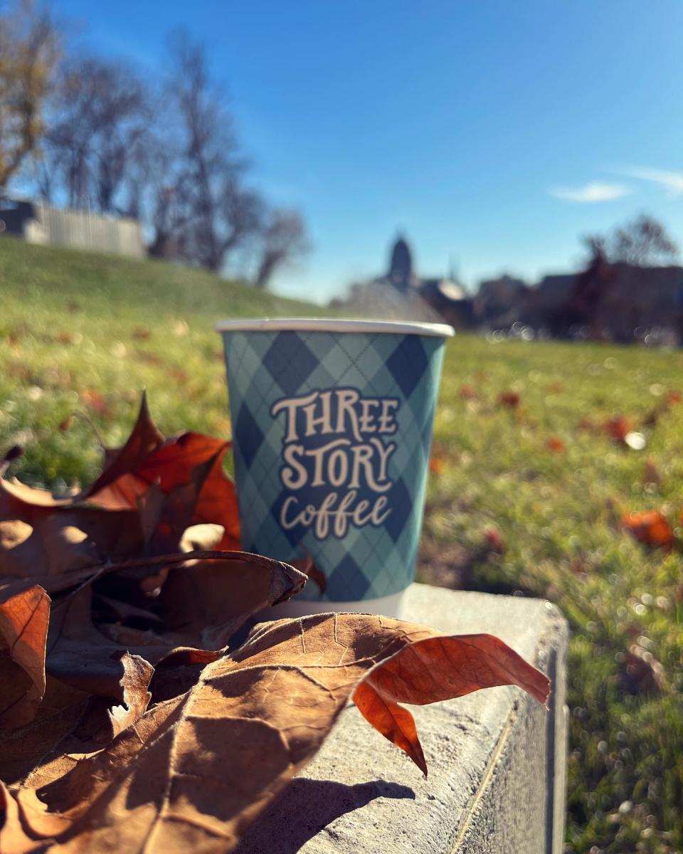 three story coffee cup in front of grass and MO State Capitol in background