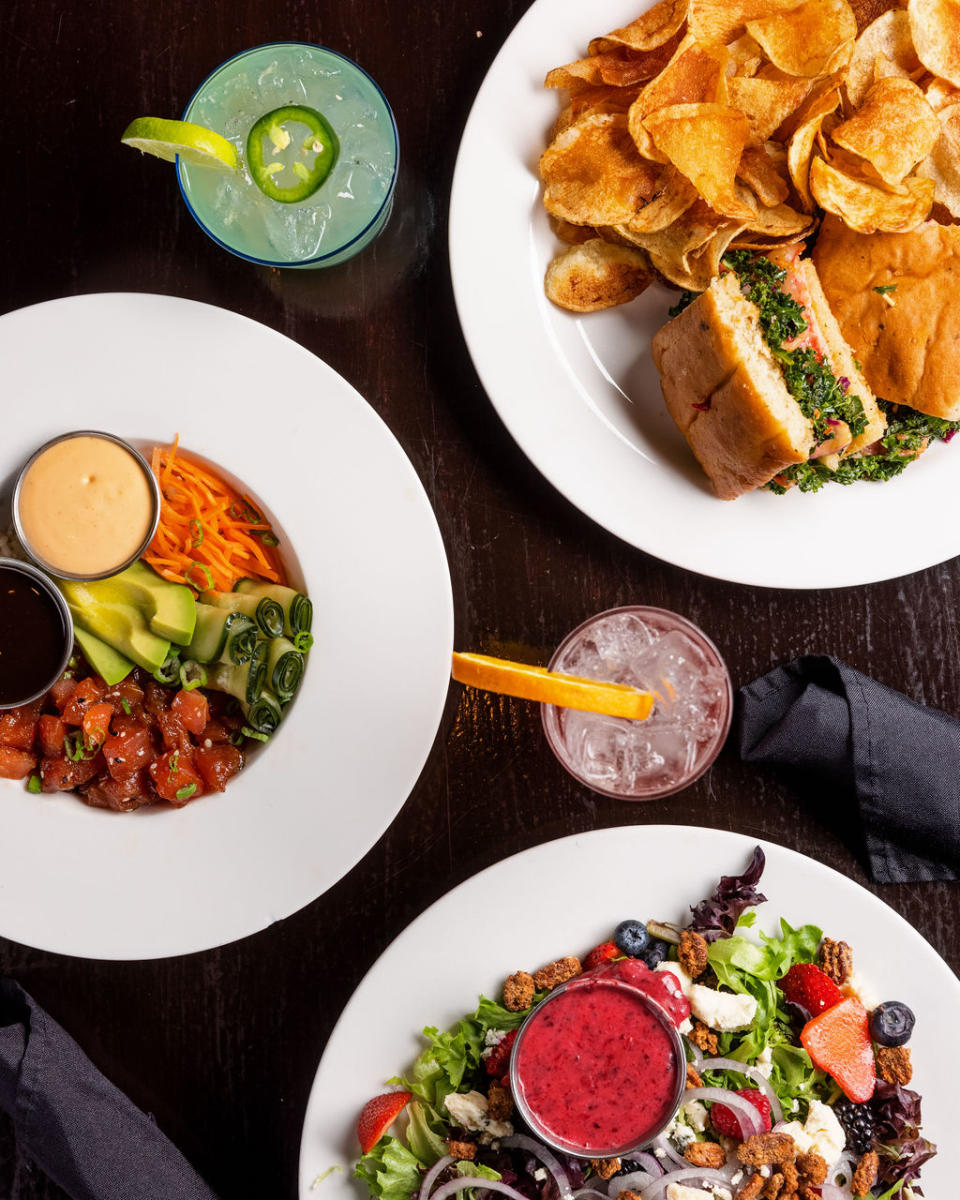 overhead shot of three plates of food and two drinks