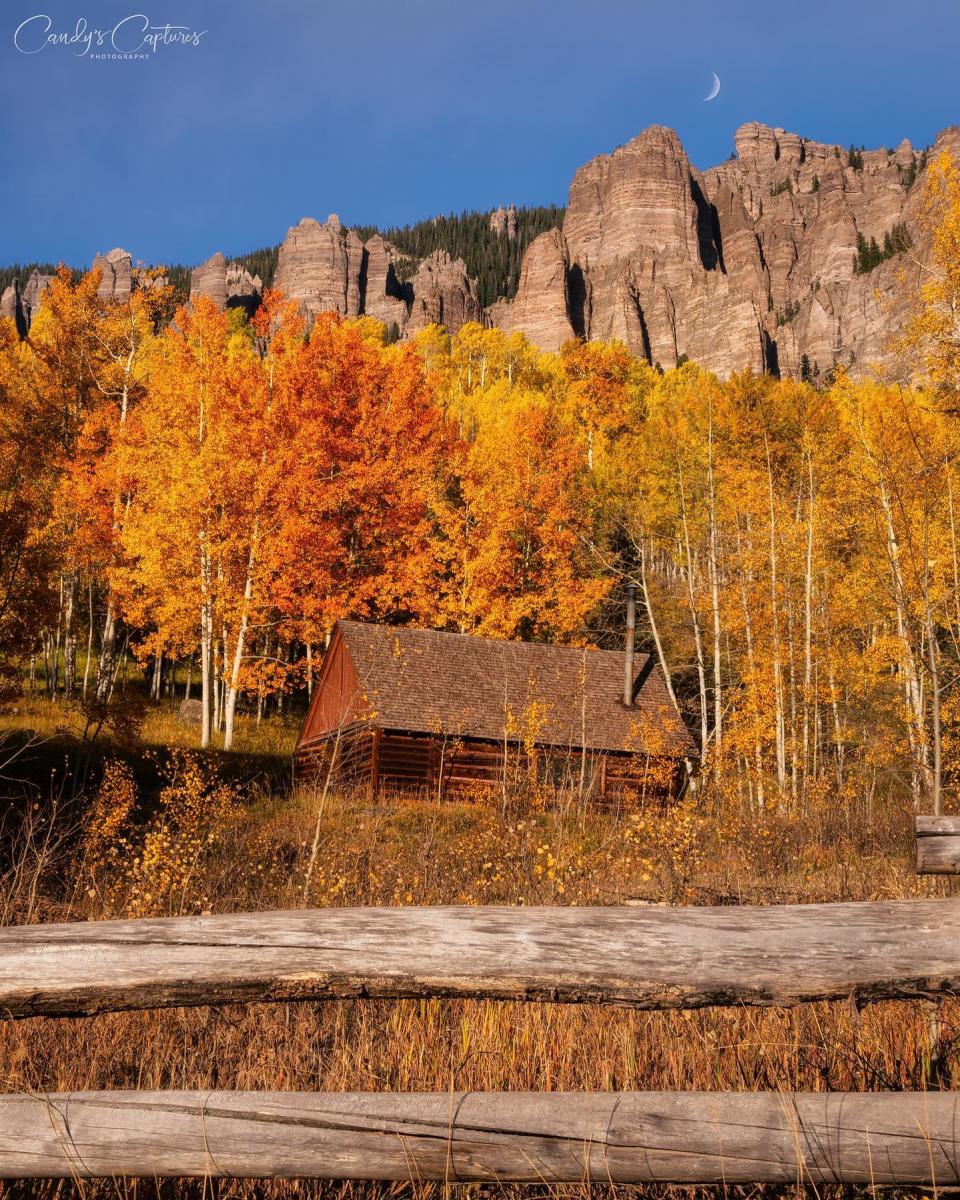 @CandysCaptures Cabin surrounded by yellow and orange aspens with mountains on Owl Creek Pass