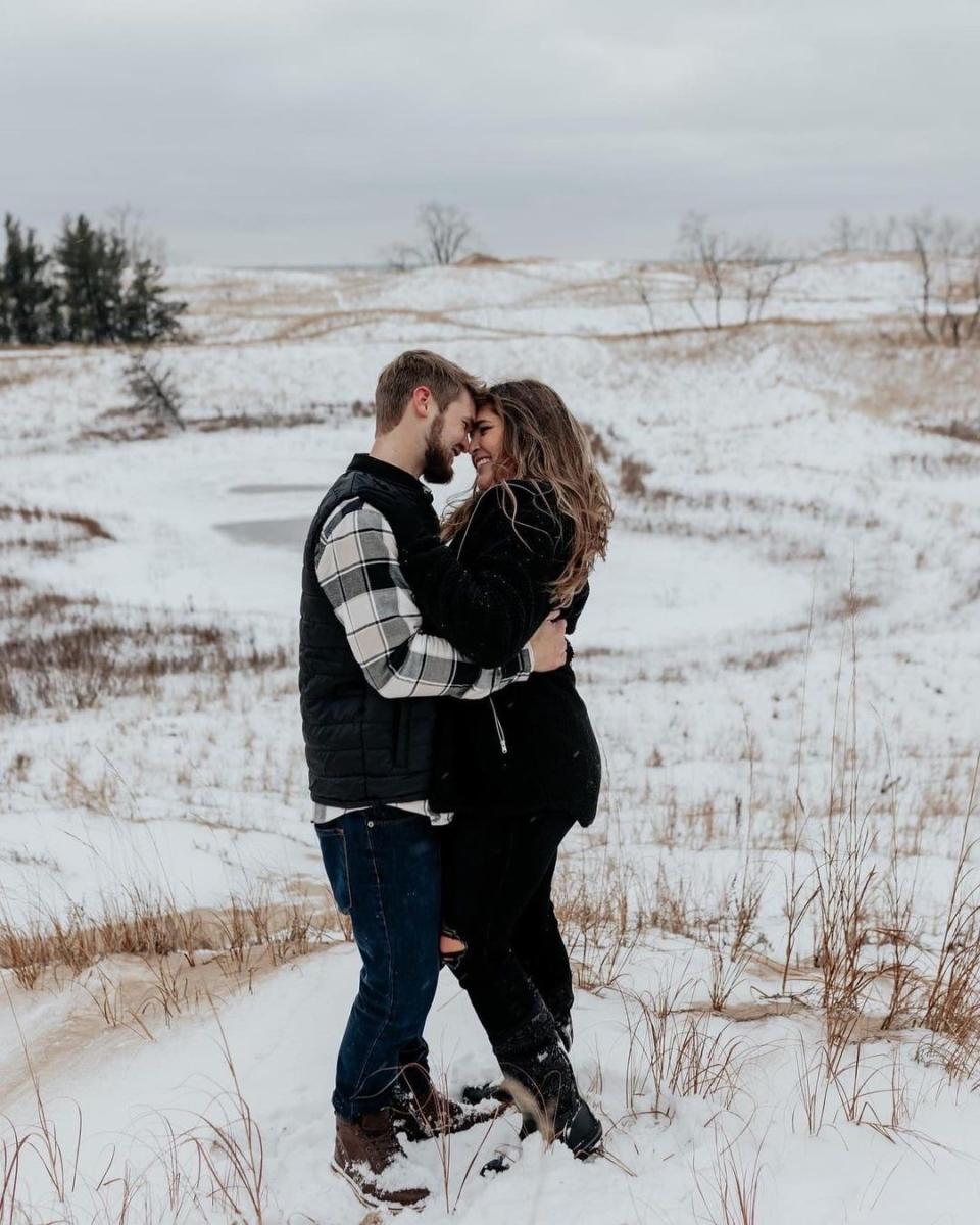 couple in winter clothing embrace on snow covered beach