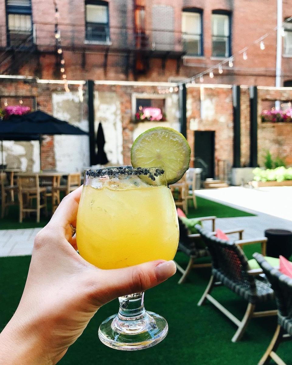A yellow summer cocktail held up outside on the brick patio of Coppin's restaurant in the Hotel Covington in Northern Kentucky.