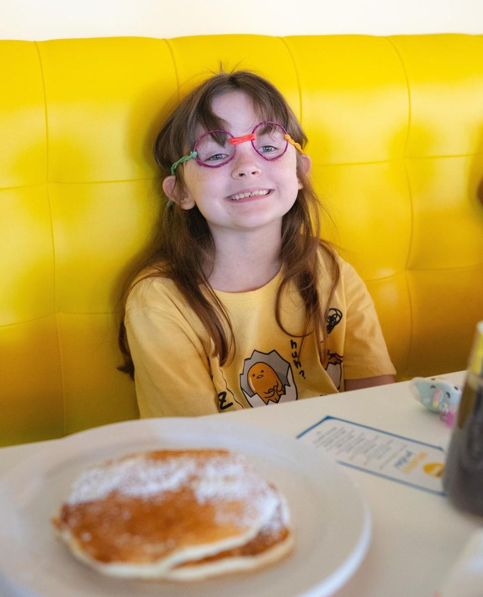 child at table with plat of pancakes
