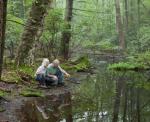 Picture of two people looking into the water of a pond.