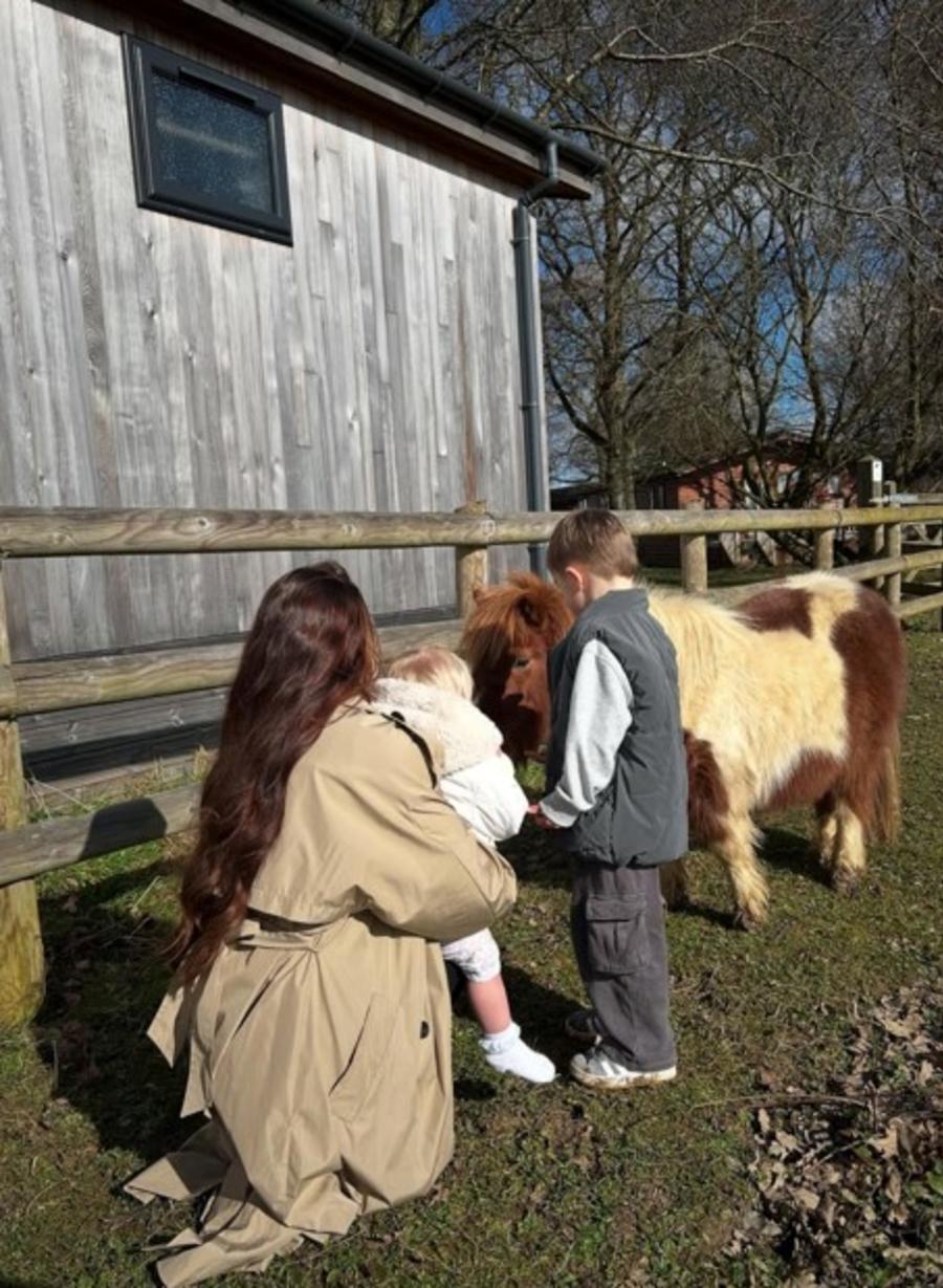 Mum and con stroking a pony outside a lodge