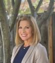 Meet Cambridge: Marya Keegan from Body Honour Coaching. A white woman standing side onto the camera smiling with trees behind her