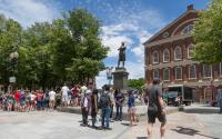 A group of visitors pause at the Samuel Adams statue outside Faneuil Hall