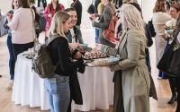 People networking at an exhibition being offered sustainable bowl food from a silver tray