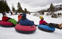 four teenagers tubing down a hill