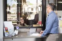 Resident speaks to City Clerk at front desk while filling out paperwork