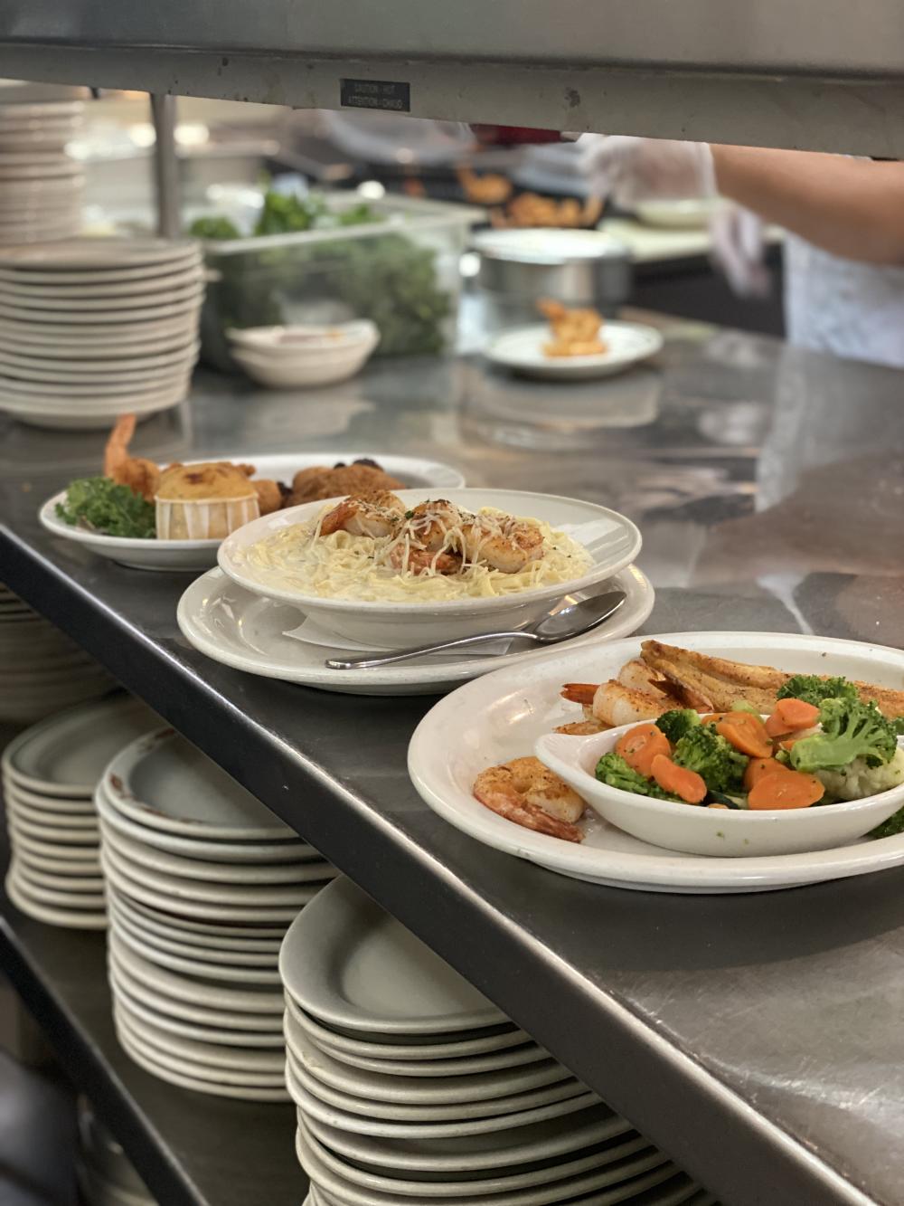 Prepared dishes including shrimp pasta,  fish fillet and fried seafood from The Schooner restaurant