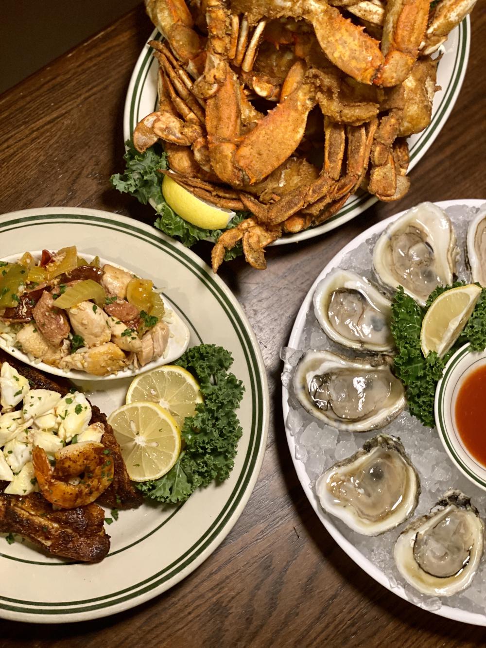 Plated dishes including fried crab leg, oysters and fillet fish at The Schooner 