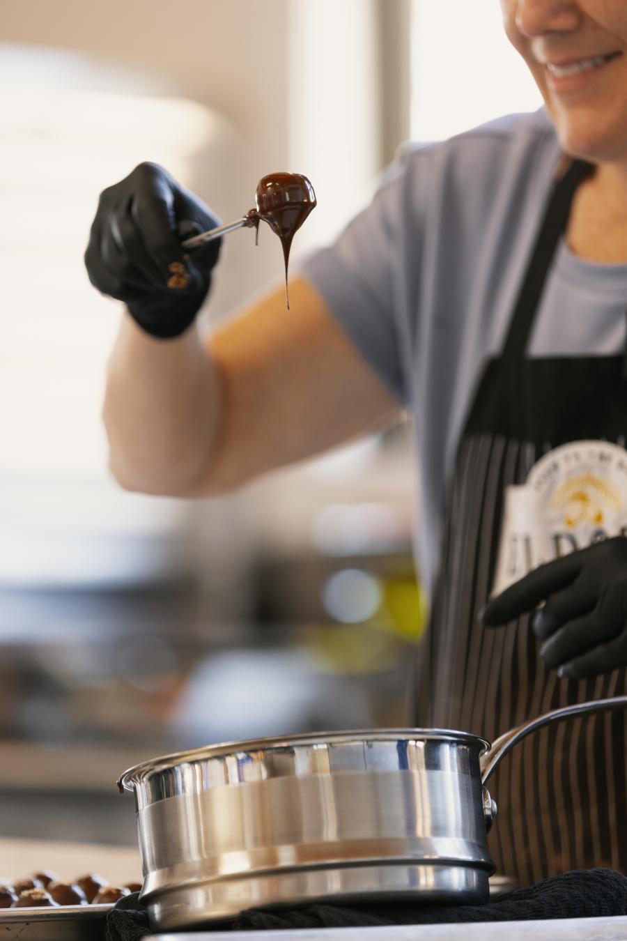 Someone dips a truffle into chocolate at Eldora