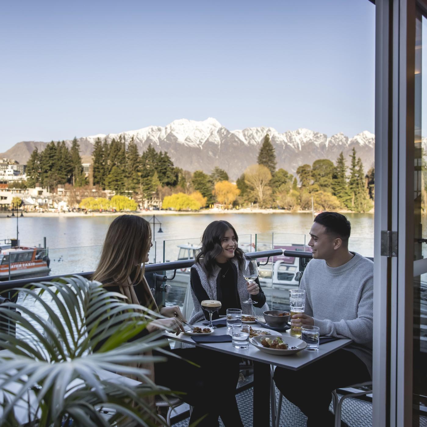 Three people Dining at Boardwalk with snowy mountains in the background