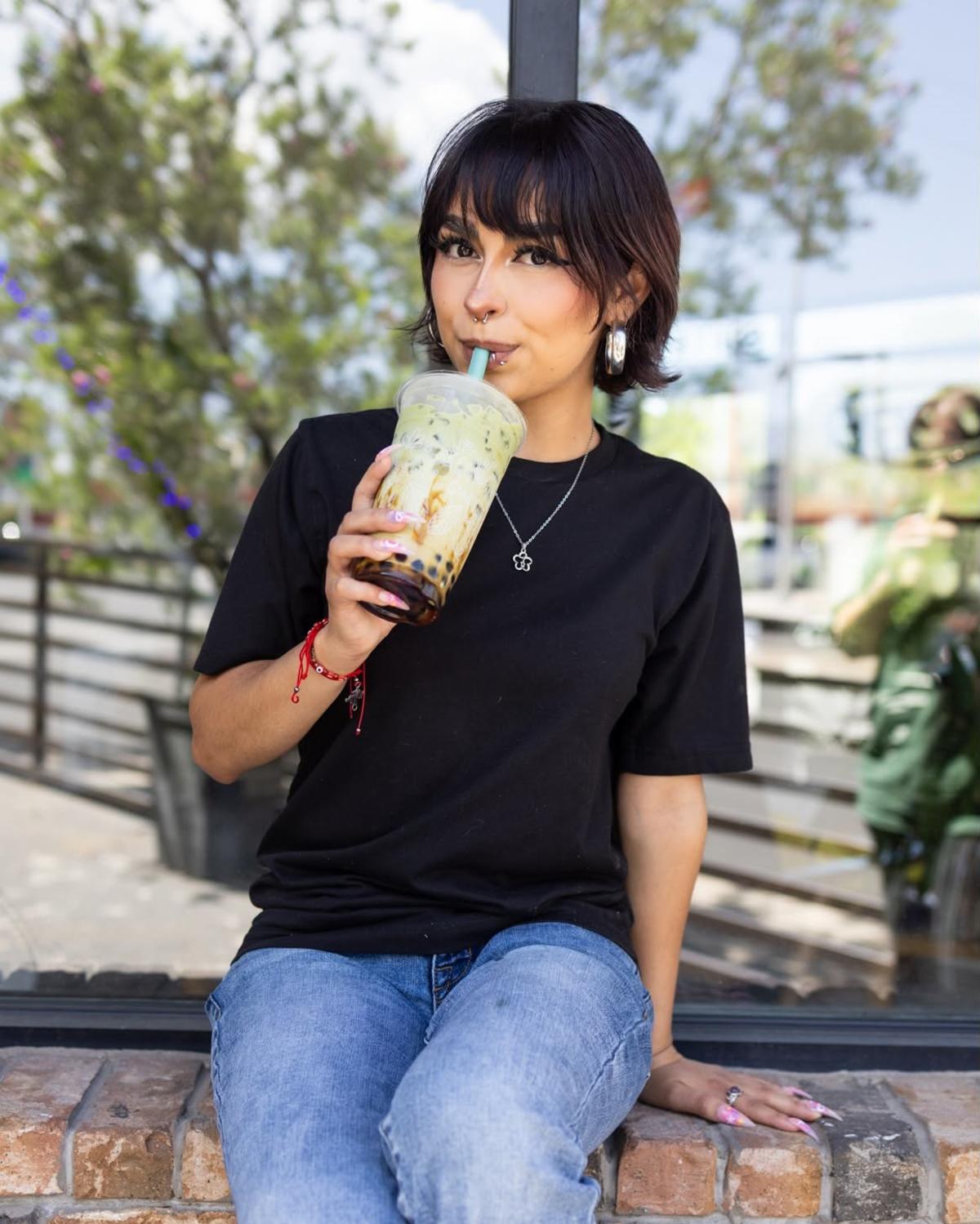 A woman drinks a matcha boba drink from The Sweet Cup.