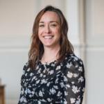 Headshot of a white woman in a black floral top, Freya Vaughan, Conference Manager, Newnham College Cambridge