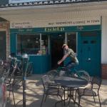 Picture of CycleUp Cafe + Bike Shop owner Chris riding a bike in front of the shop.