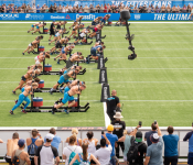 A group of competitor push sleds with weight on them across a field
