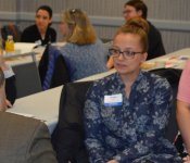 Event participants listen intently while seated at a table