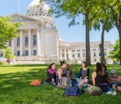 A group of people sit around a blanket and enjoy a picnic on the Capitol lawn