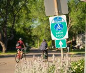 Bicyclists ride past a Lake Monona loop sign