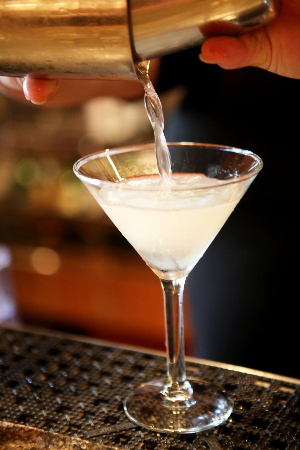 A smoky white drink is poured into a martini glass.