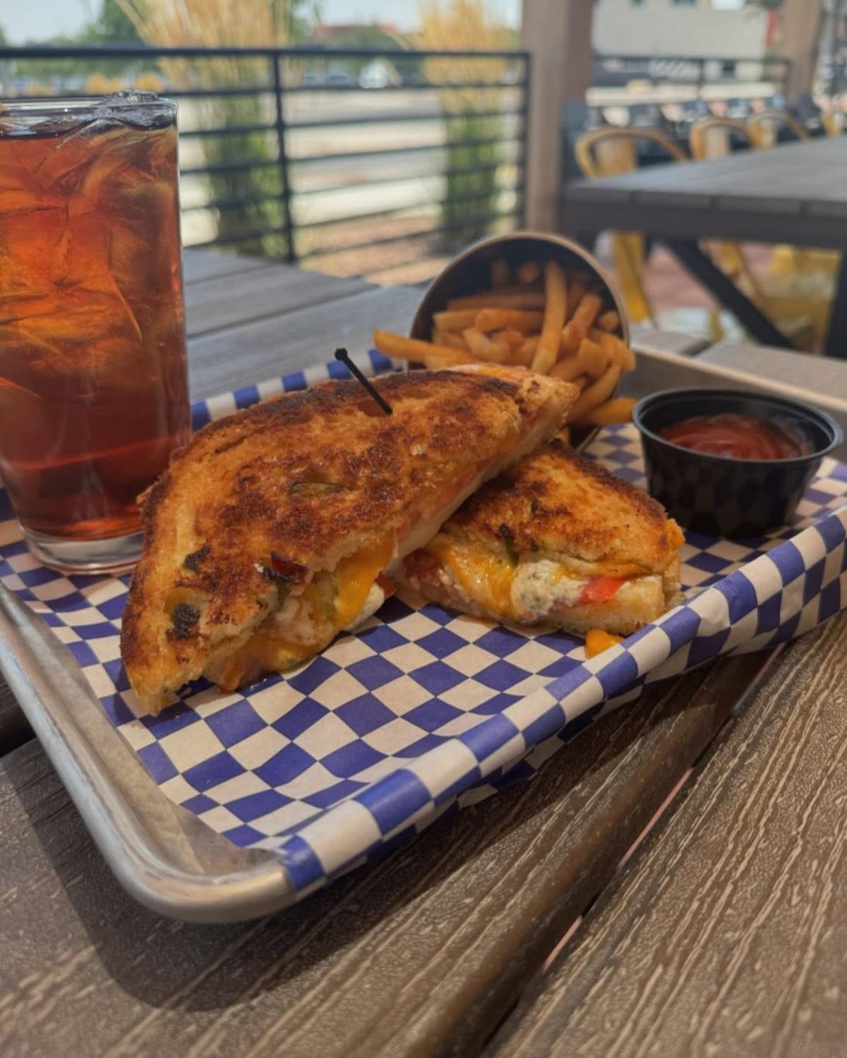 A photo of the soon to be famous grilled cheese, made with house made green chile bread, caramelized onions, sliced tomato, and garlic aioli, and grilled to perfection from 12th Street Tavern.